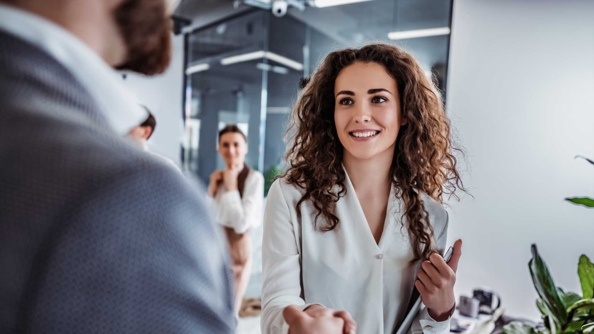A woman shaking hands with one of his co-workers for accepting a project.