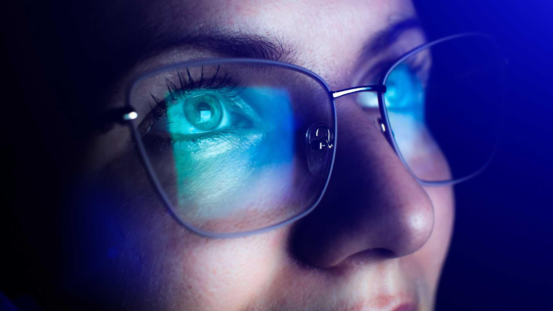 Woman with glasses looking at a screen.