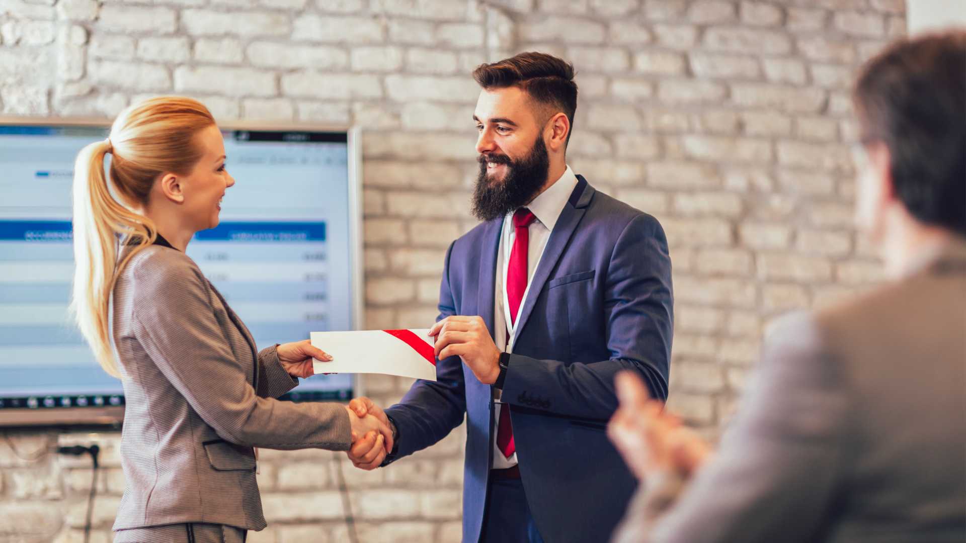Female and male coworkers shaking hands on a business deal.