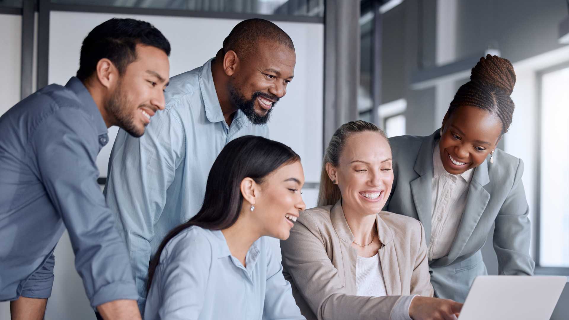 Group of Co-workers together looking at work on laptop.