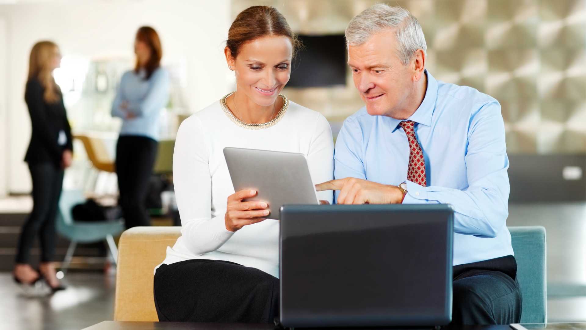 A man and woman using tablets and computer for training.