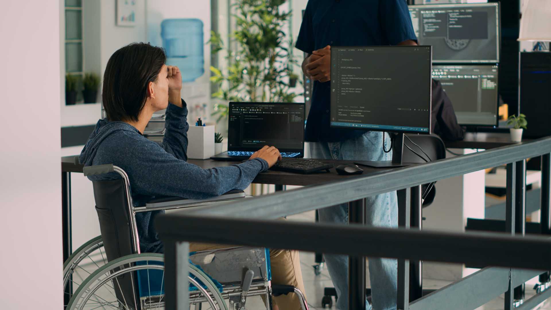 Man helping out a coworker on his coding computer.