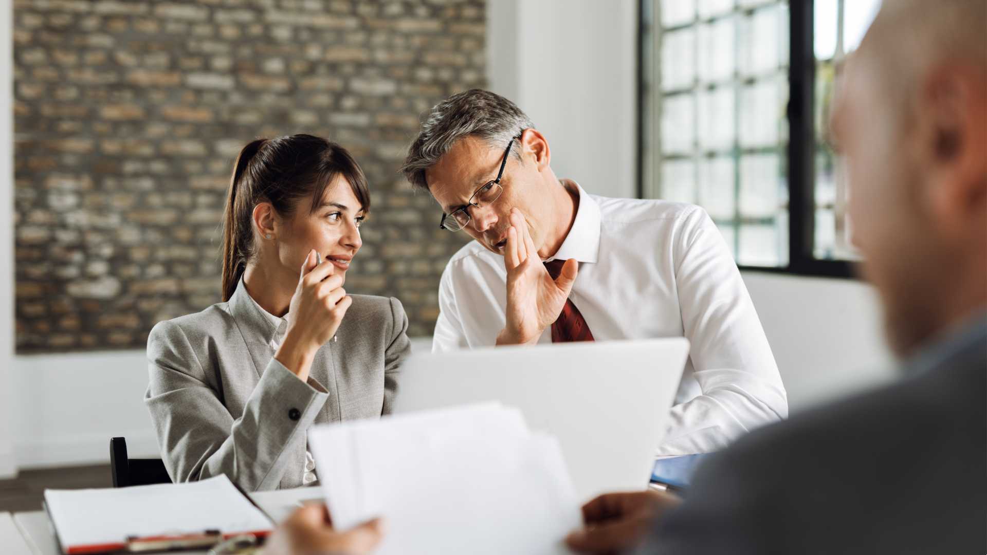 Businessman whispering something to his coworker.