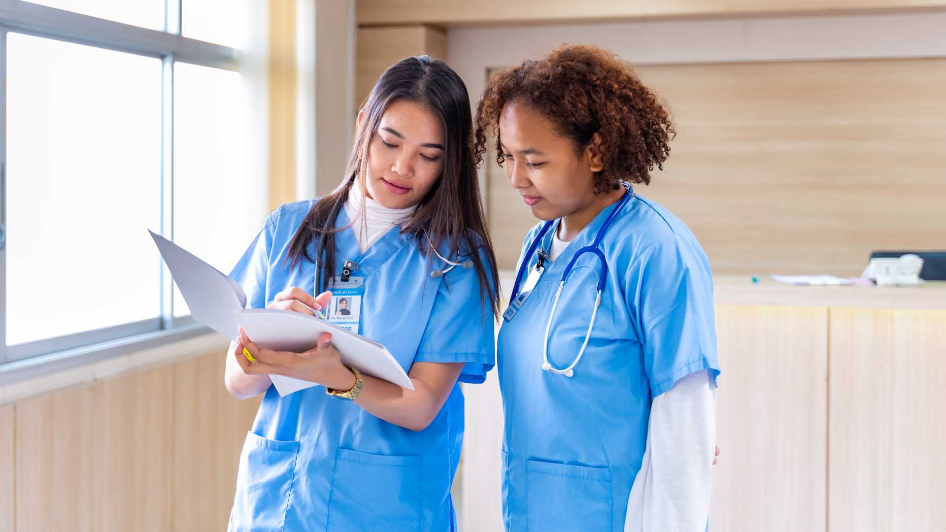 Nurse talking to eachother, reading a file.