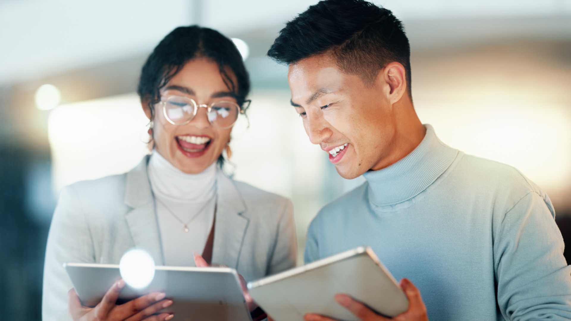 A man and woman together using tablets for work.
