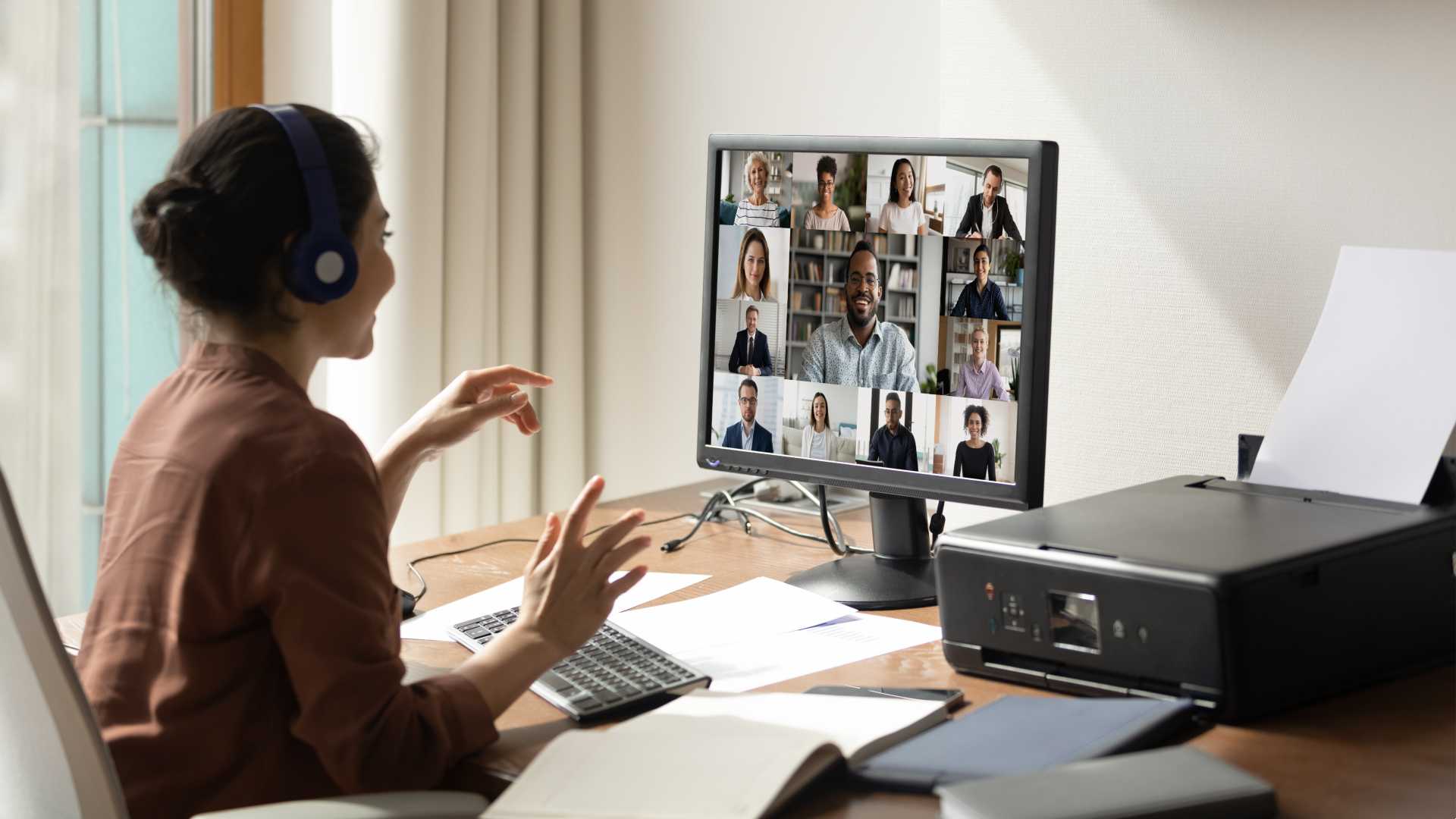Woman working remotely in home office and doing a zoom call.