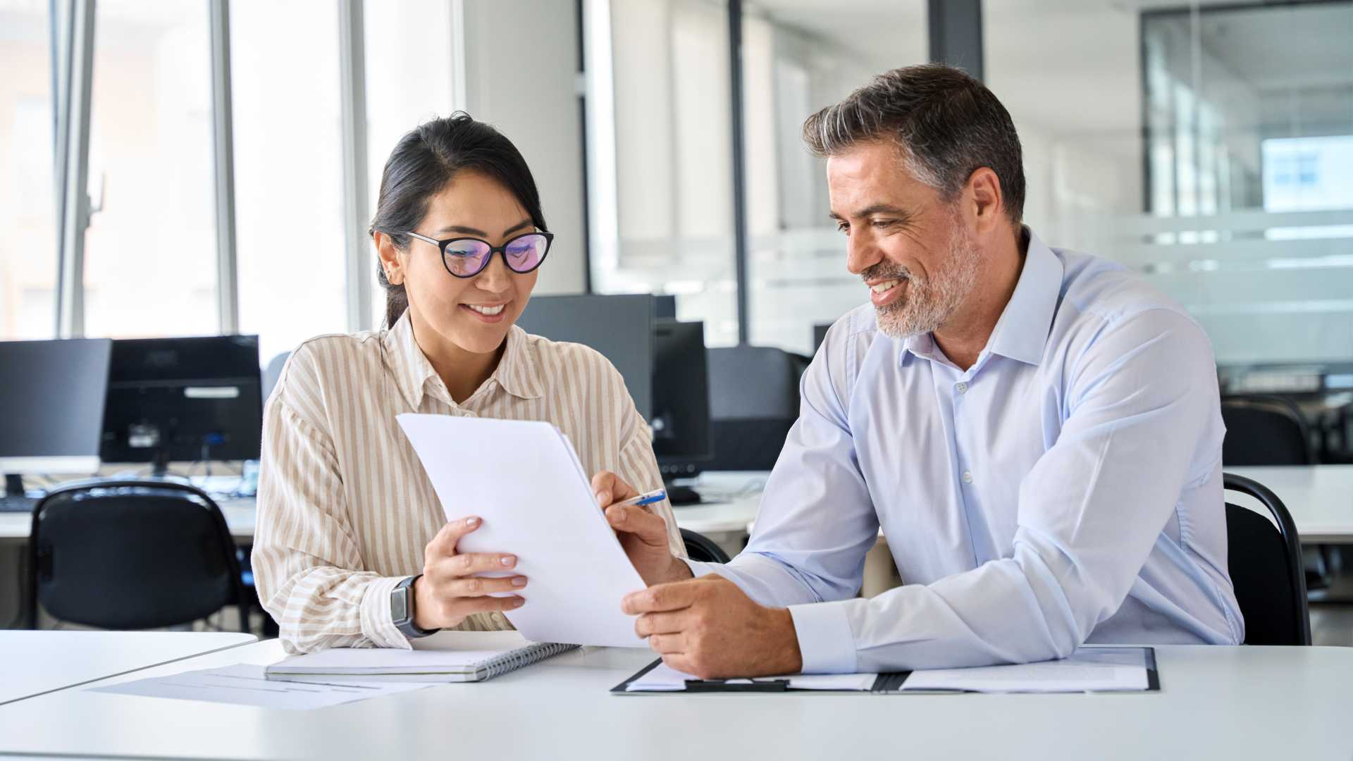 Younger woman with older male coworker working on a project.
