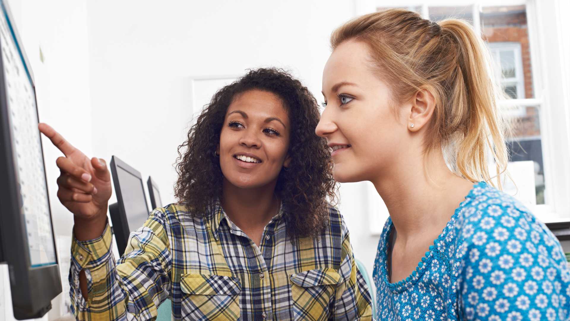 Manager training new employee on a desktop.