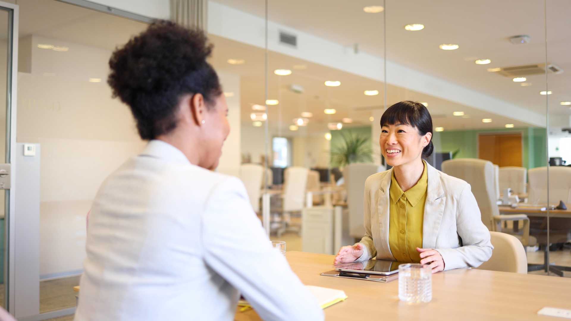 Two women in a business setting seated and facing each other during a conversation