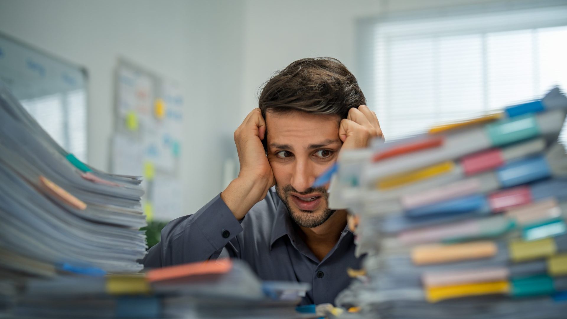 Guy sitting a pile of papers for work.