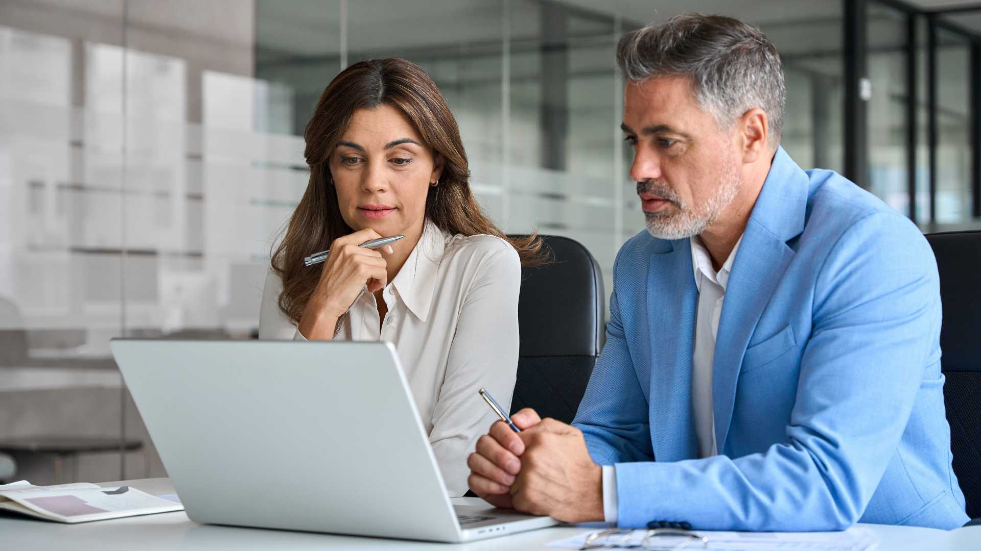 two professional employees looking at a laptop