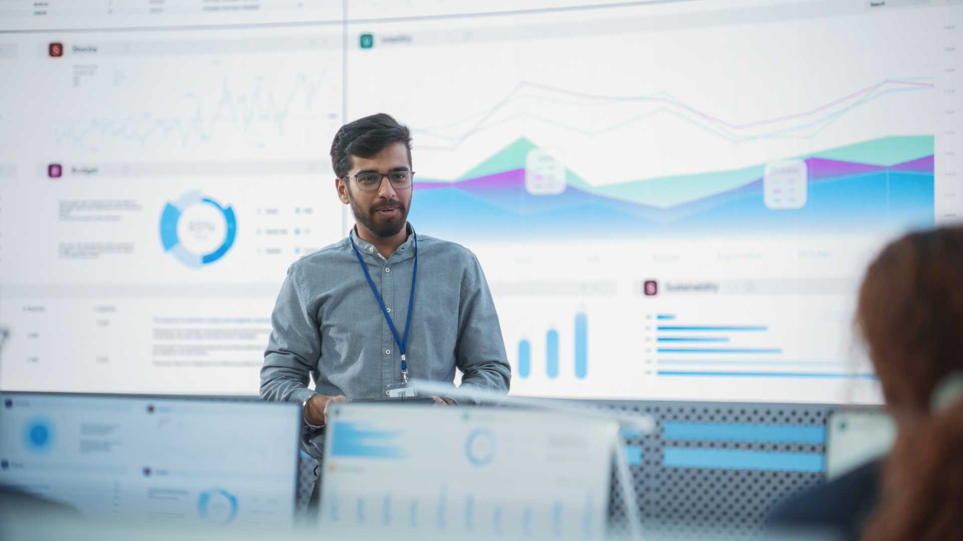 Business professional presenting performance metrics and analytics dashboards to colleagues during a meeting, illustrating IT certification, workforce capability and data-driven decision-making.