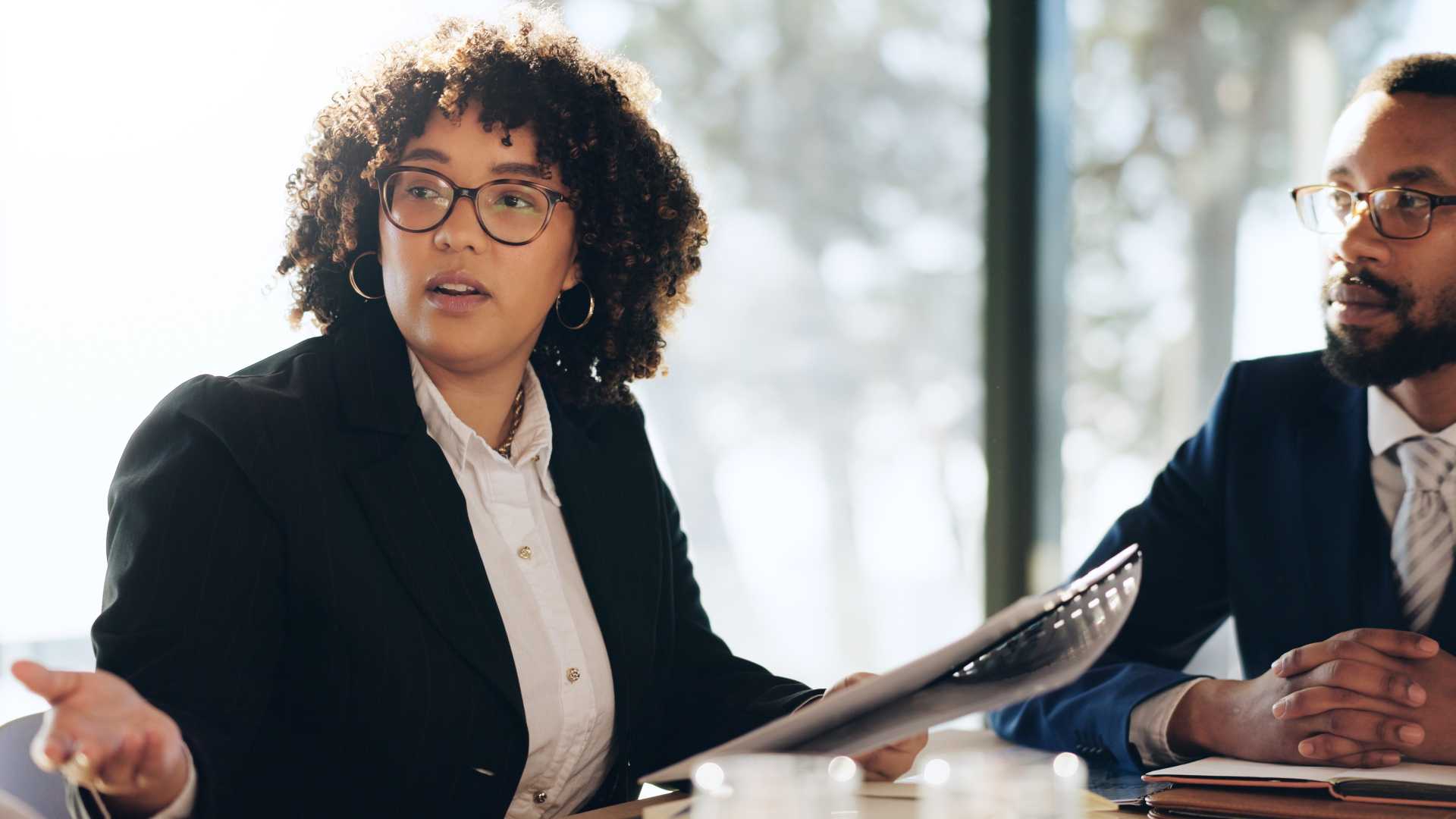 Leader facilitates a workplace discussion with a colleague during a team meeting, illustrating leadership development through real-world communication, decision-making and behavioral practice.