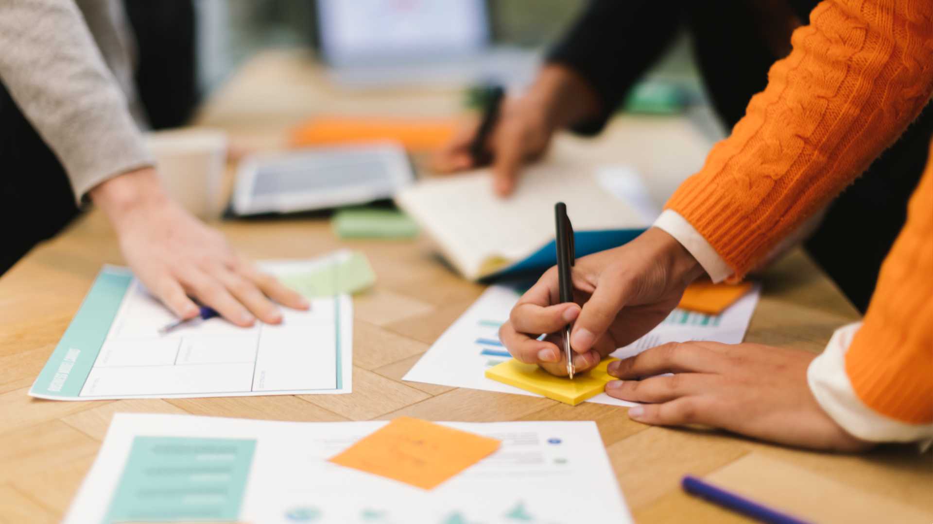 Hands of colleagues working at a table with documents spread out