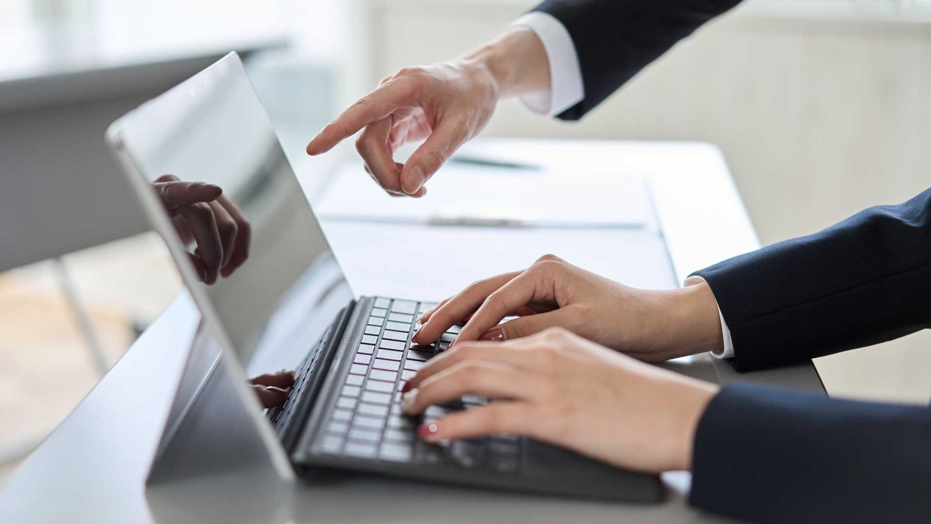 Manager points to a laptop screen while coaching an employee, illustrating how clear performance standards, guidance and feedback reinforce workplace learning and improve employee performance.