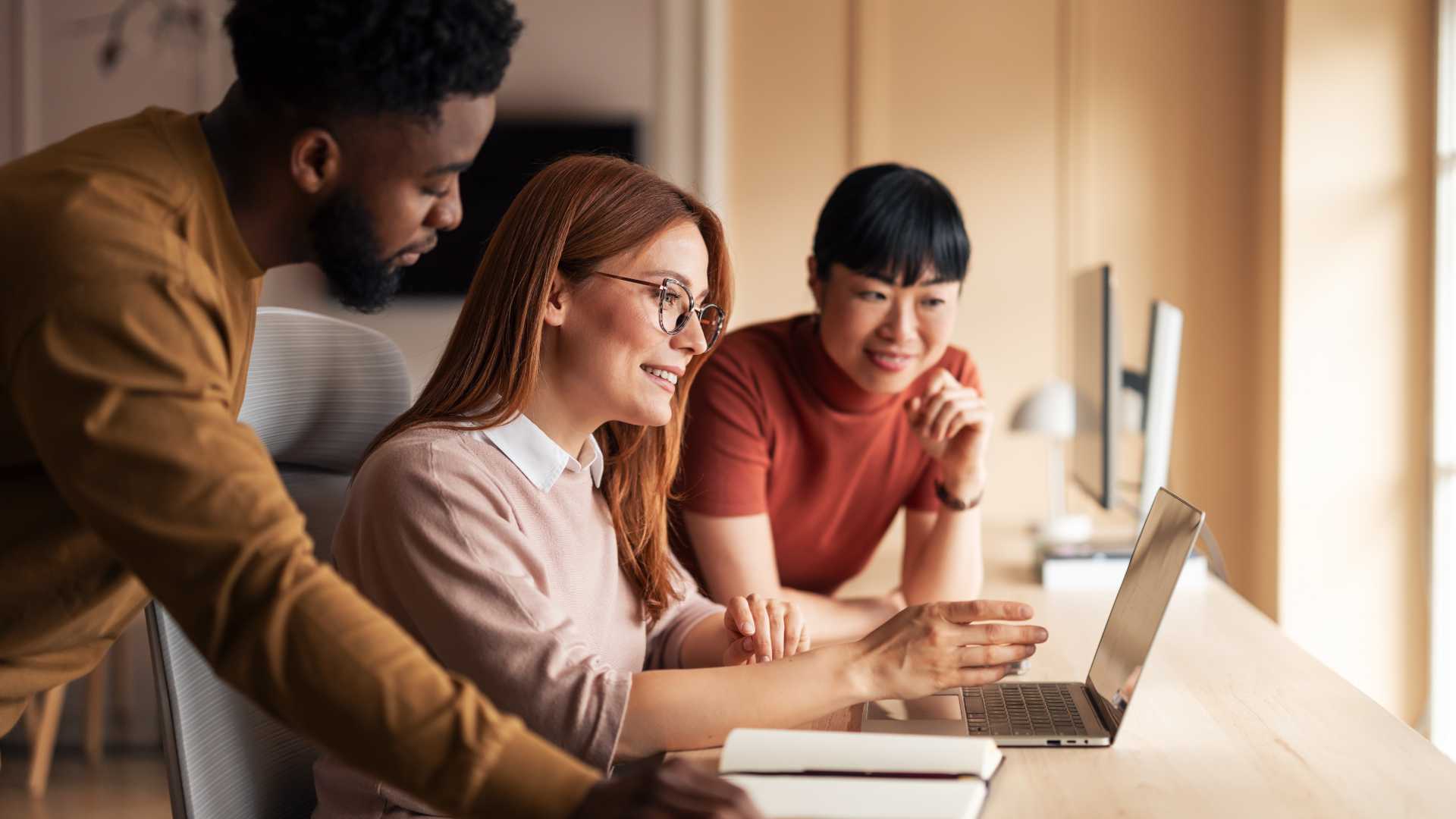 Small team collaborates around a laptop, illustrating agile planning, knowledge sharing and scalable learning strategies in a startup environment.