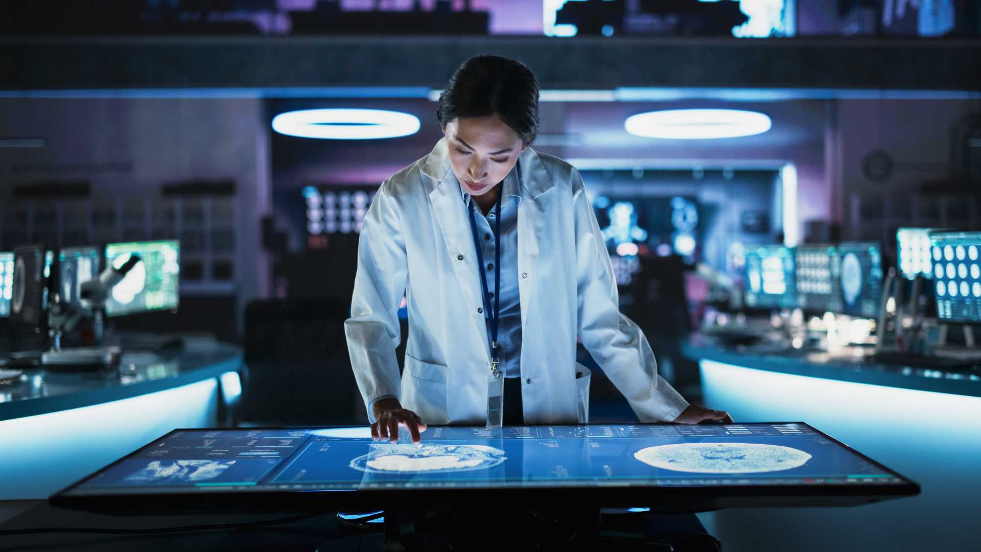 healthcare professional in a medical lab using a large interactive touchscreen to review patient scans and clinical data in a modern healthcare setting