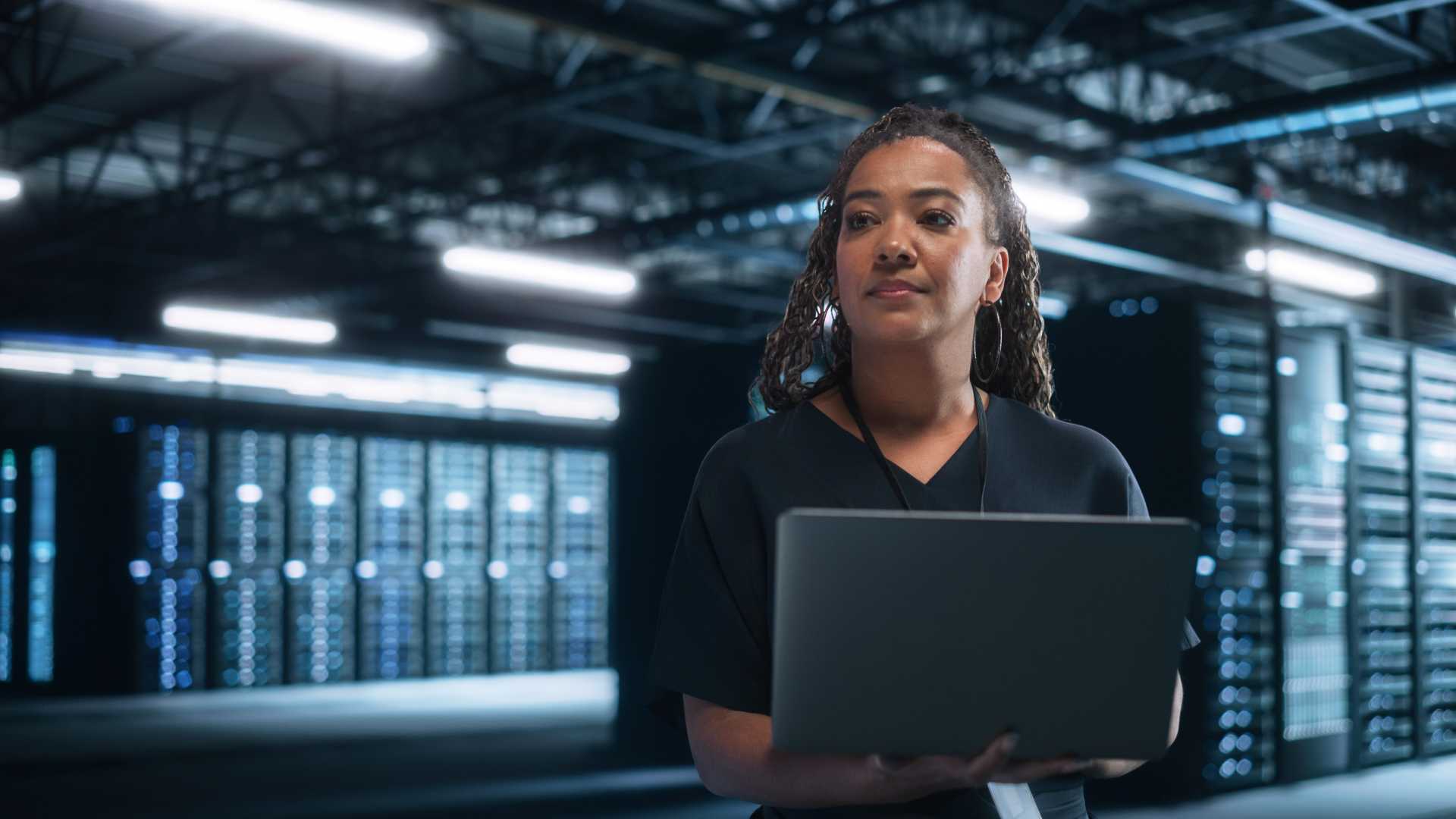 professional using a laptop in a data center, representing AI transformation, digital infrastructure and workforce capability development