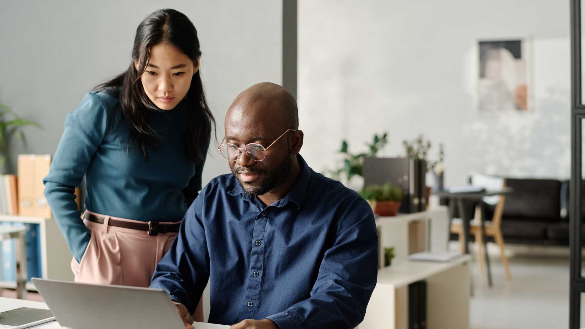 Manager and employee review information together on a laptop during a workplace development conversation.