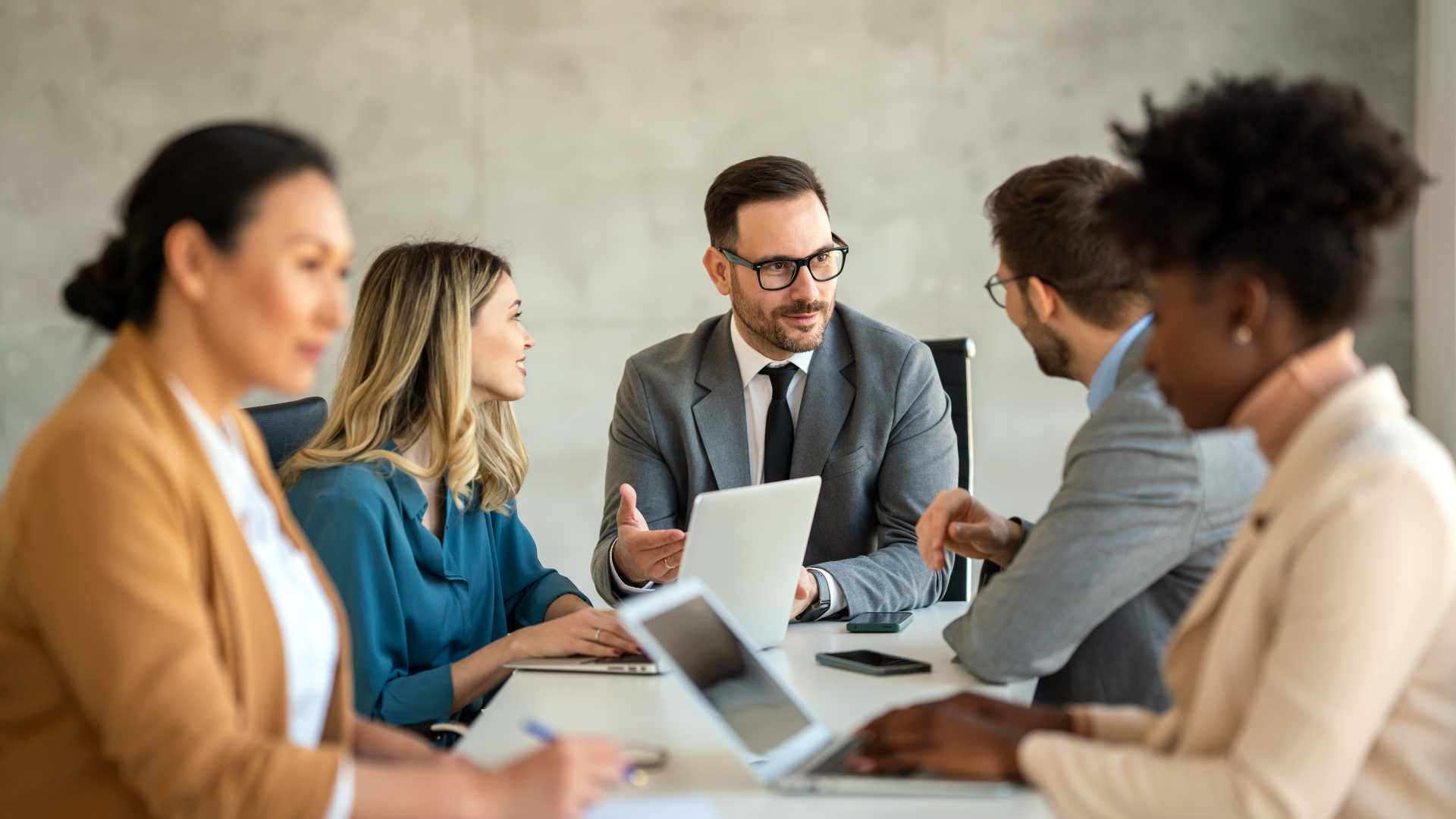 Business leader facilitating a collaborative discussion with a diverse group of employees during a workplace meeting.