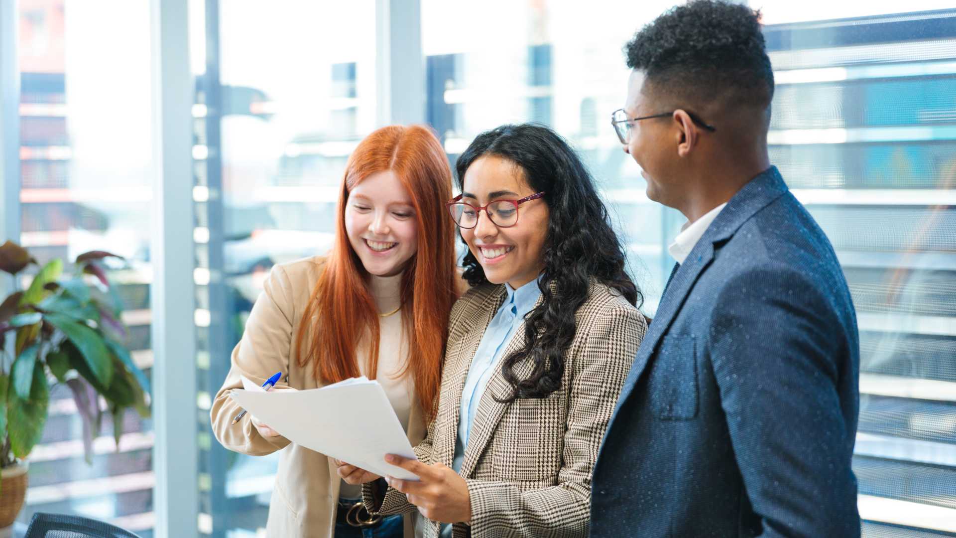 Sales manager and team members review documents together during a collaborative workplace discussion.