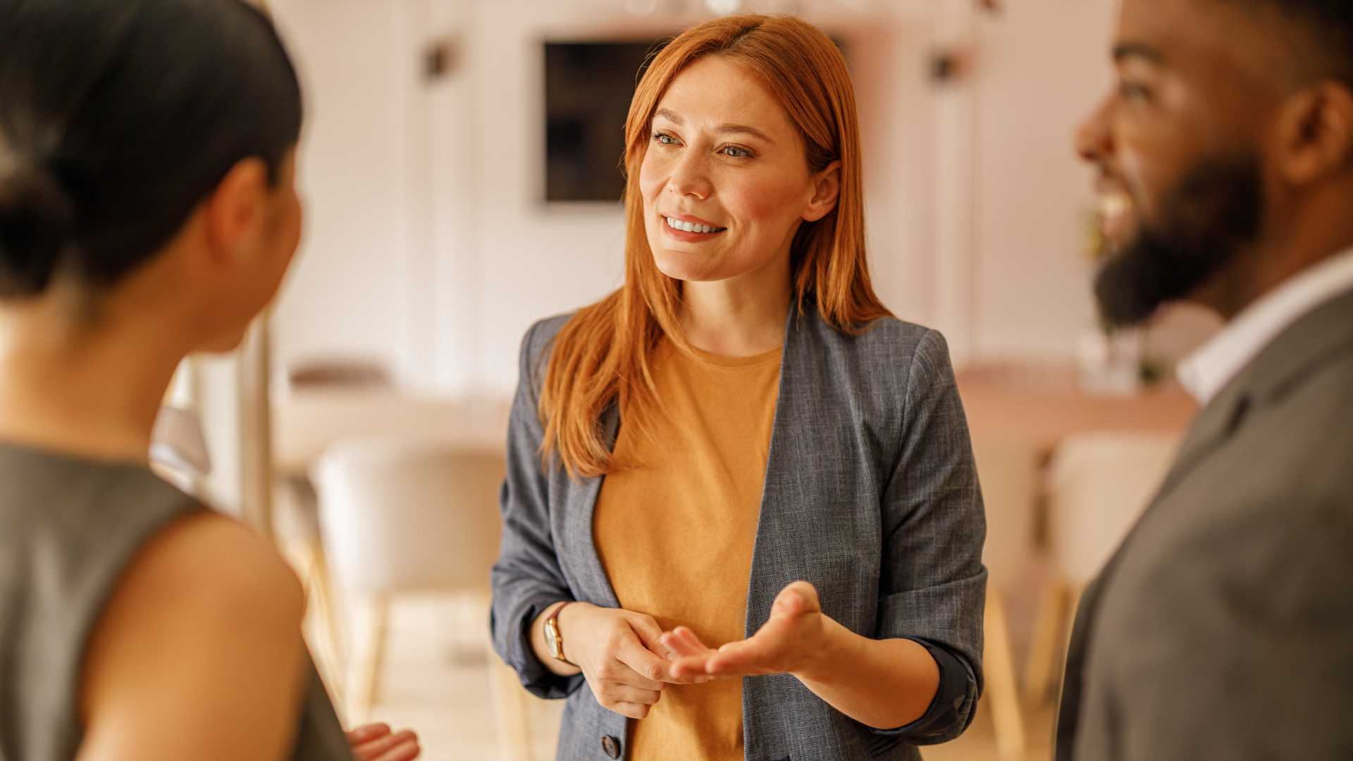 Manager speaks with two employees during a workplace conversation, illustrating trauma-informed leadership, active listening, psychological safety and supportive communication.