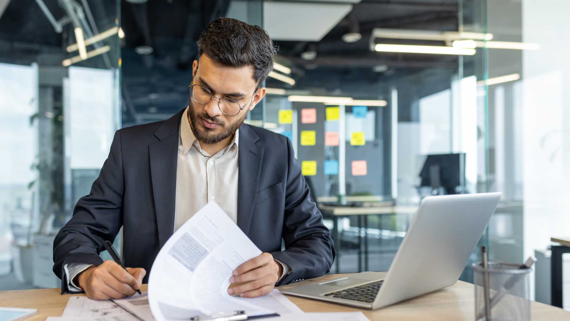 Professional reviewing performance reports beside a laptop, representing learning measurement, training effectiveness and the evaluation of business impact.