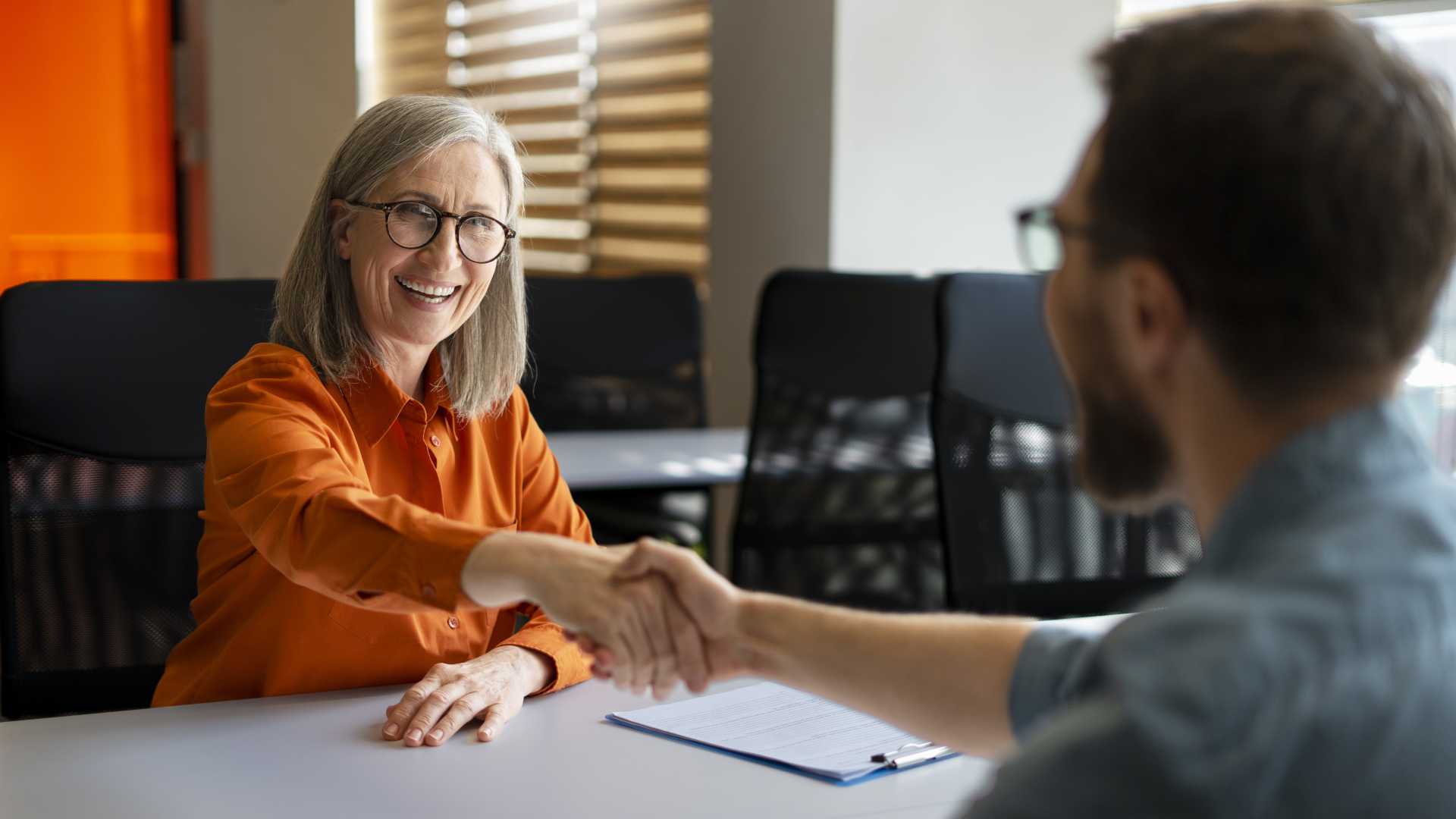 Sales professional greeting a client with a handshake, illustrating relationship building, buyer conversations and field readiness during the sales process.