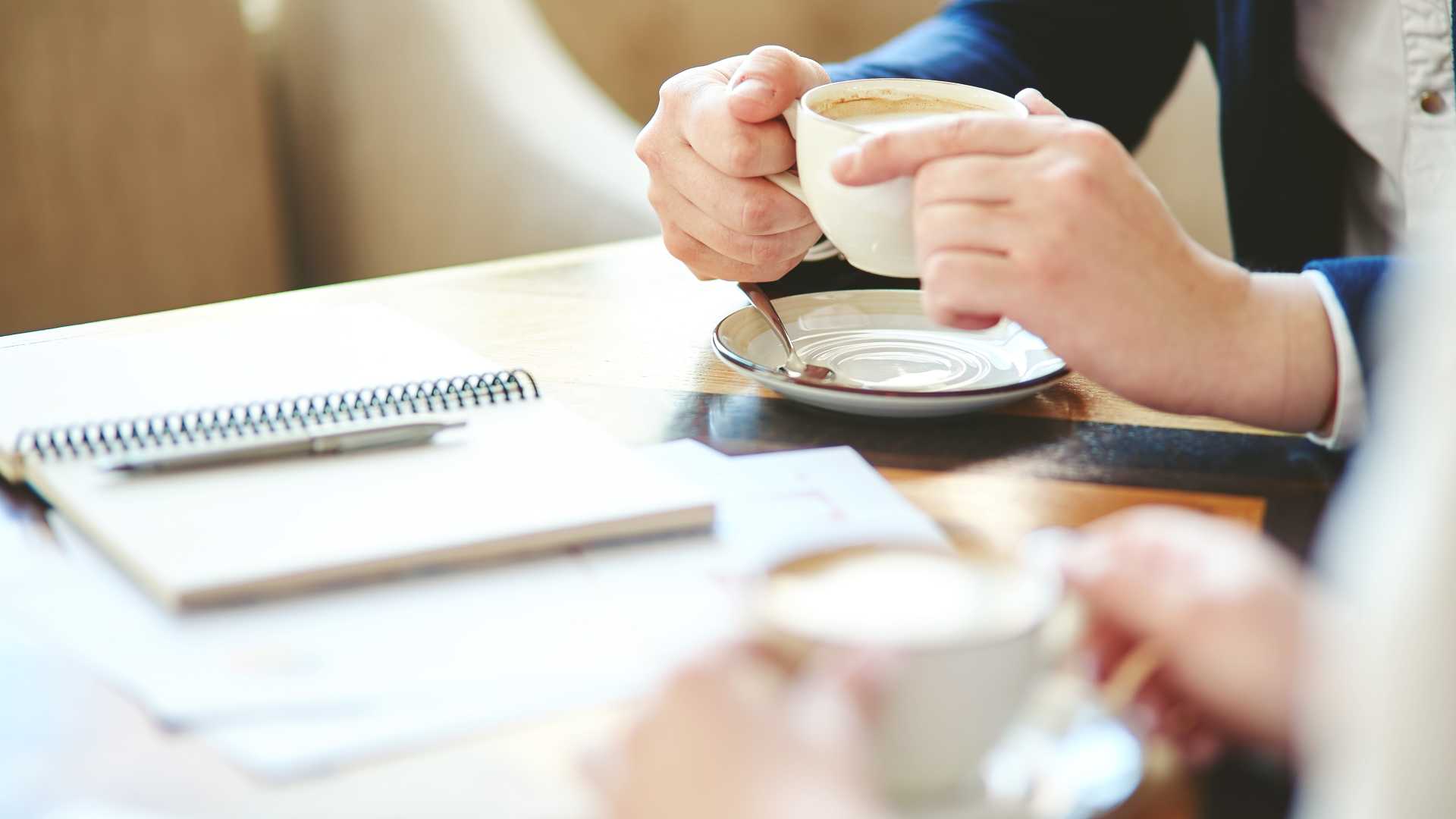 Colleagues having an informal workplace conversation over coffee, illustrating how everyday employee recognition can strengthen connection, confidence and engagement.