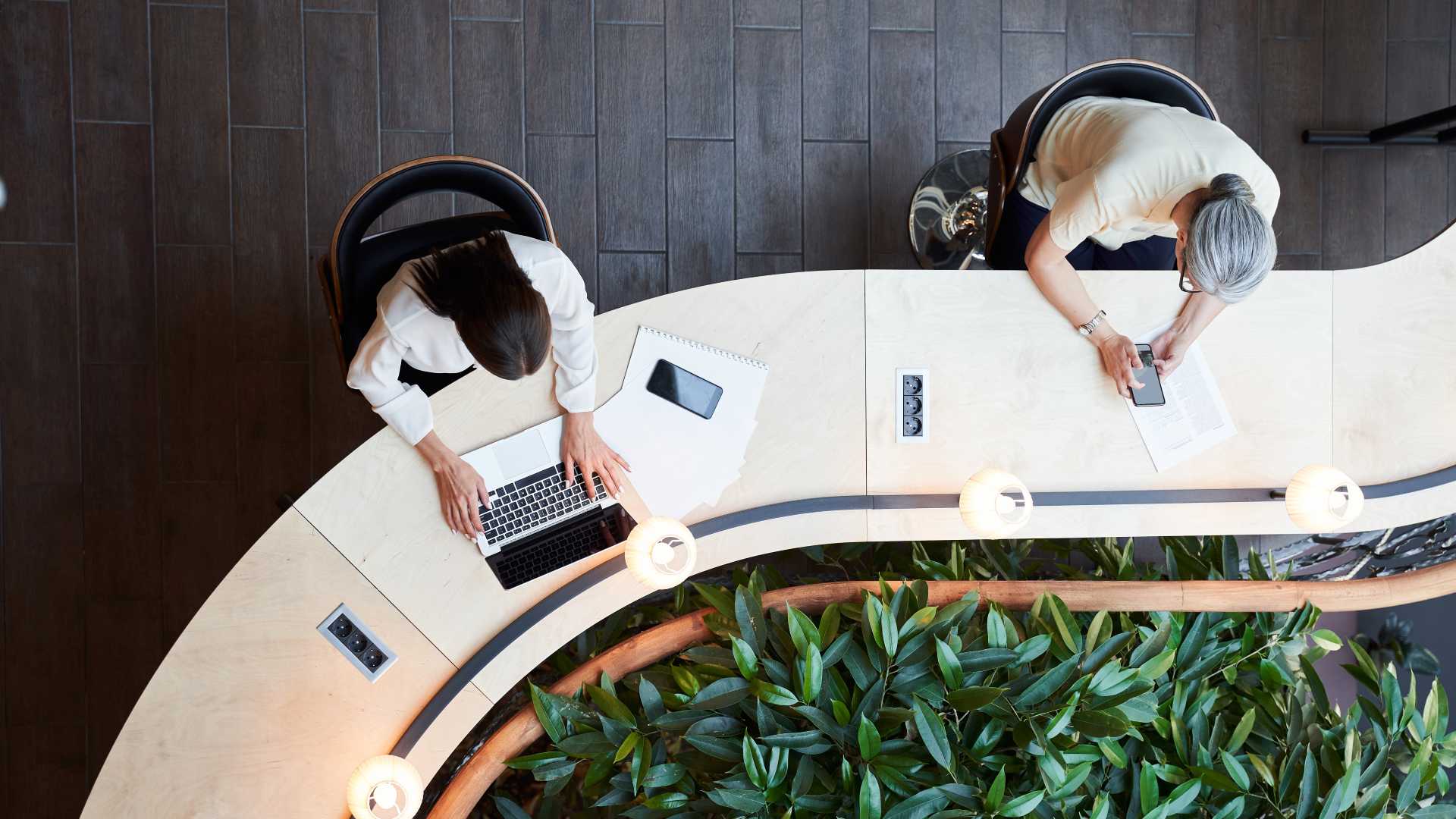 Employees working with digital tools in a shared workspace, illustrating the importance of examining workplace realities and performance needs before designing training.