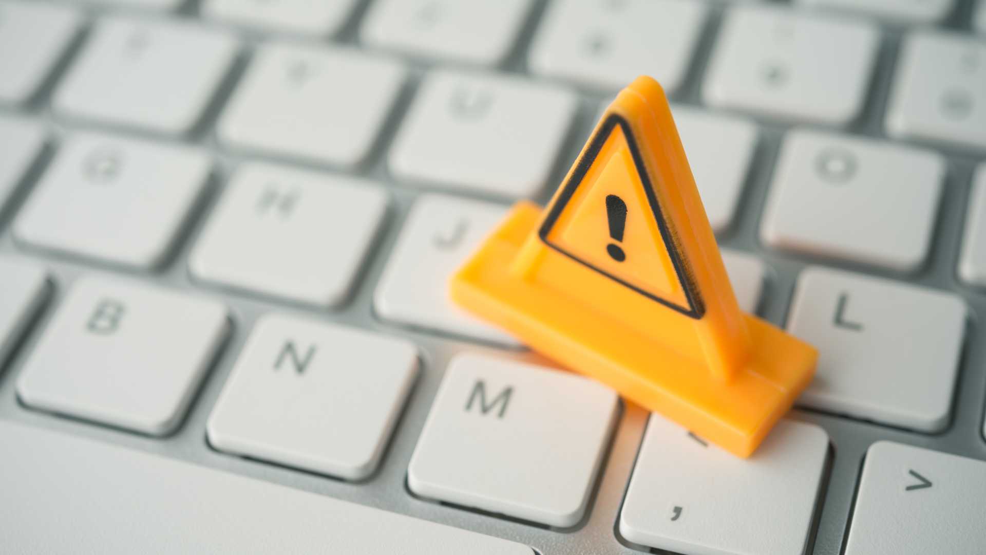 Cybersecurity warning symbol on a computer keyboard, representing digital threats, phishing risks and the need for continuous cybersecurity awareness training.