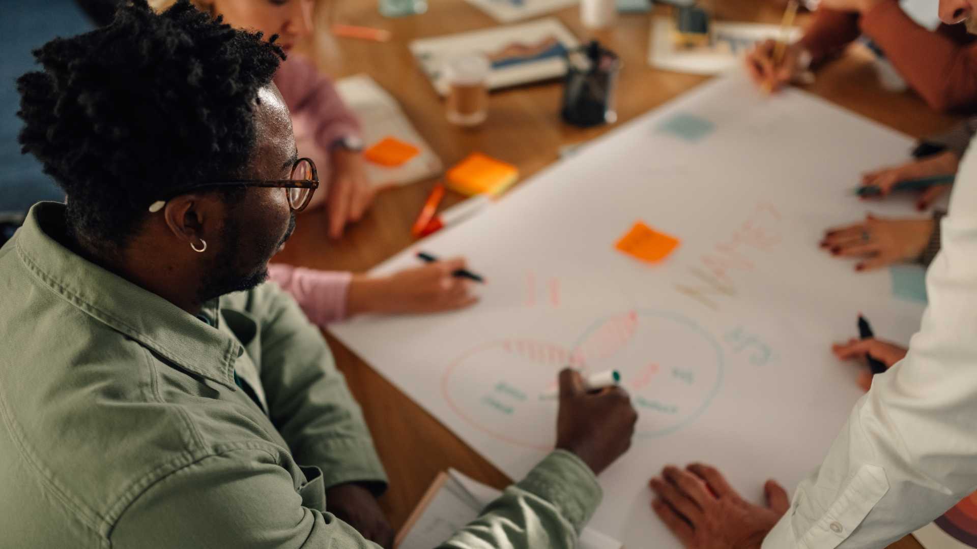 Business professionals collaborating on a strategic planning diagram, illustrating how L&D governance supports training prioritization, business alignment and shared accountability for organizational goals.