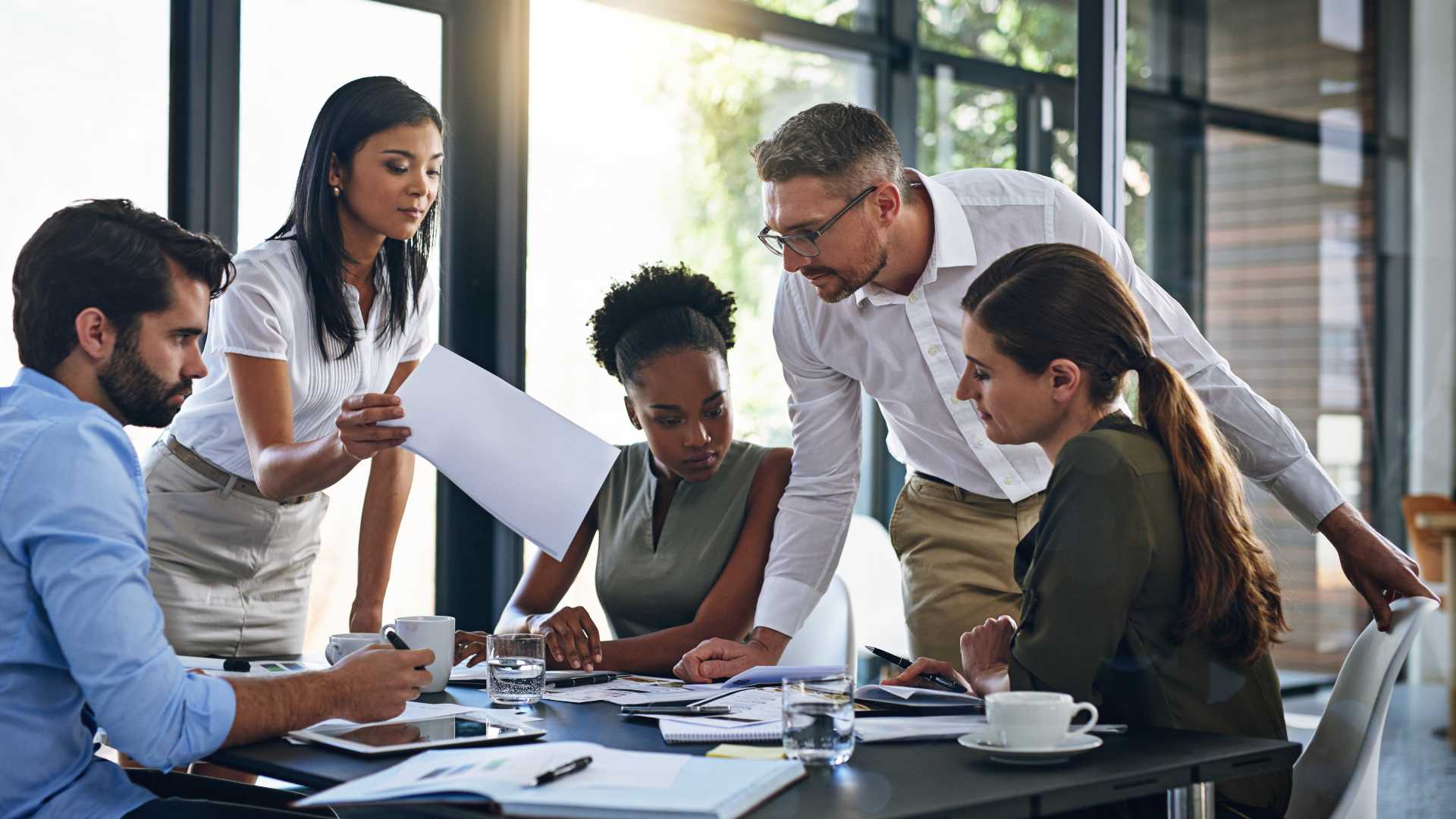 Business professionals collaborating around a table, illustrating how performance enablement connects learning, coaching and workplace support to improved employee performance and business outcomes.